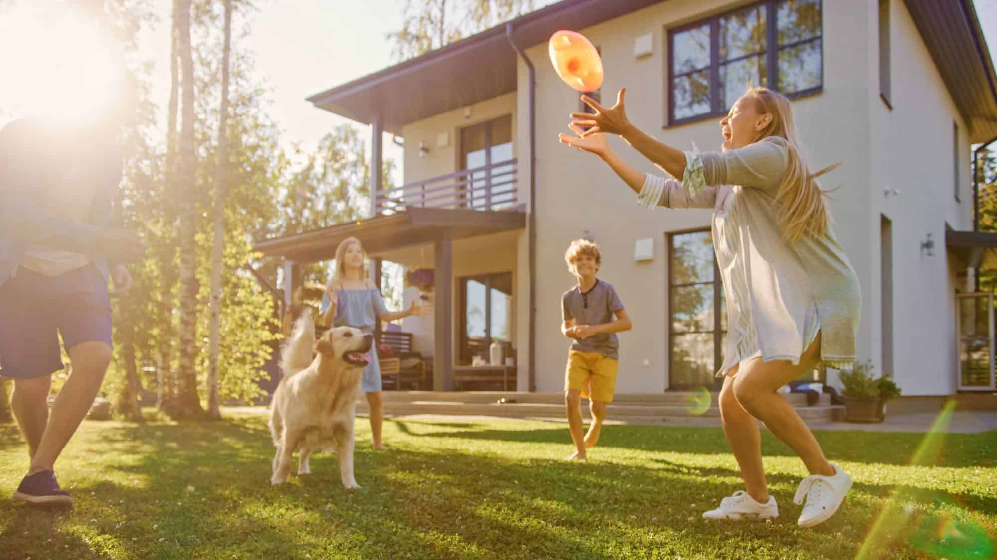 Happy family playing football with pet golden retriever.